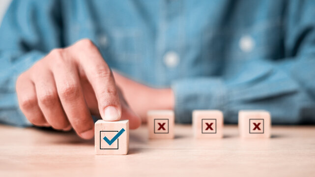 Businessman select blue correct sign mark between Red Cross mark which print screen on wooden for approve and reject business project proposal concept.