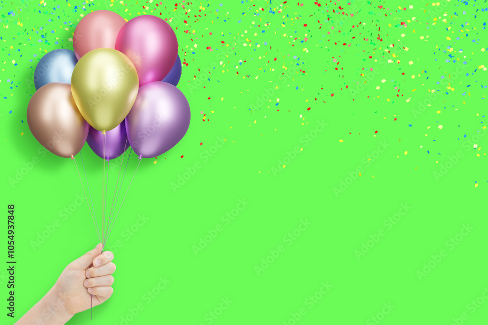 Poster female hand holding bunch of shiny colorful balloons on green background with confetti. empty space 