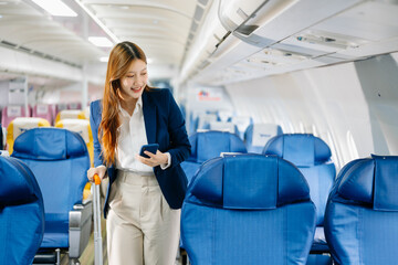 Asian female passenger of airplane sitting in comfortable seat while working laptop and tablet. Travel in style,