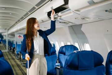 Asian female passenger of airplane sitting in comfortable seat while working laptop and tablet. Travel in style,