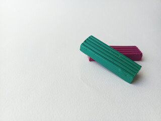 Green and purple plasticine lie on a white background. Background for advertising, place for text. Sculpting.