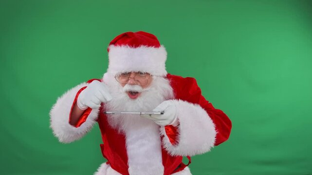 Comical Santa use tablet scrolls screen on green chromakey background. Mid shot.