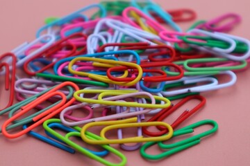 Background and texture of a Pile of colorful elliptical paper clips on a pink background, close up view.