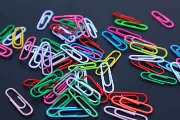 Colorful elliptical paper clips scattered on a dark background, close-up view.