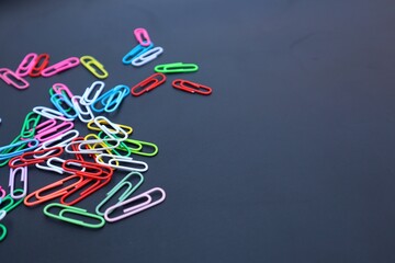 Colorful elliptical paper clips scattered on a dark background, close-up view.