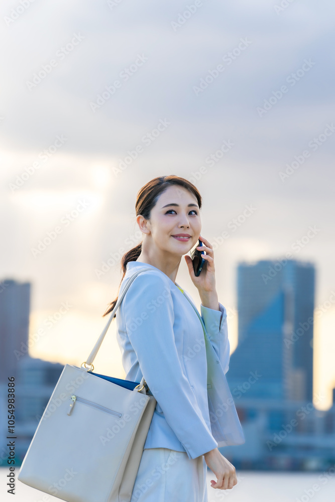 Aufkleber スマホ、スマートフォン、ビジネスウーマン、女性、電話、通話、ビジネス、ビジネスマン、日本人、笑顔、都市、社会、通信、5g、iot、連絡、アプリ、サポート、問い合わせ、話す、会話、コール、屋外、ビル群、