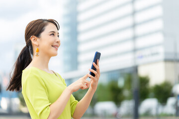 スマホ、スマートフォン、女性、ビジネスウーマン、ビジネス、キャリアウーマン、モバイル、5G、都市、通信、アプリ、屋外、社会、技術、テクノロジー、携帯電話、ソーシャルメディア、ソーシャルネットワーク、SNS、ビル群、都会、笑顔、仕事、ビジネスマン、日本人、立つ、コピースペース、webサイト、道路、インターネット、オンライン、メール、送信、人材、20代、30代、歩く、転職、就職、展望、若い、キャリア、 © metamorworks