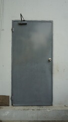 The door of a gray room at the back of a building
