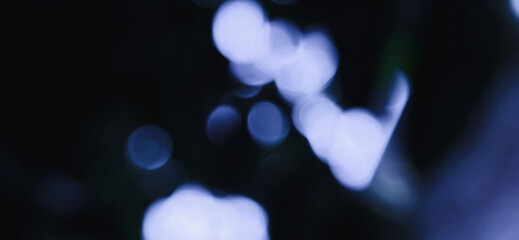 Blurred image of blue light sources in a dark background, creating a bokeh effect. Dark bokeh photo with blurred light, Background for banner.