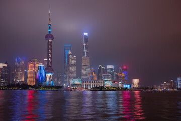 Obraz premium Shanghai colorful skyline with motion speed light of passing ferry in the foreground at night - Shanghai, China