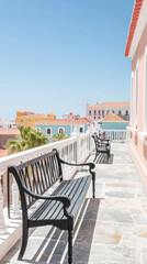 Fototapeta premium Colorful buildings and benches on a sunny terrace in a coastal town
