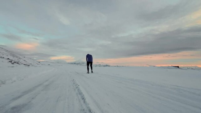 Aerial drone view of young man jogging outdoors with snowy mountains in the background. Healthy running and exercise concept outdoors, high-speed drone fvp shooting, slow motion