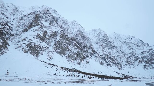 A snowy winter landscape in Jispa, Himachal Pradesh, India. The snowcapped peaks of the Himalaya mountain Range during moody winter day.