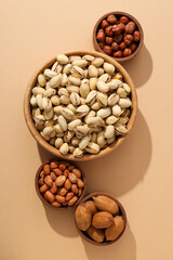 Various nuts in wooden bowls on a beige background