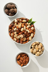 Various nuts in white bowls on a white background