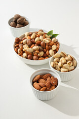 Various nuts in white bowls on a white background