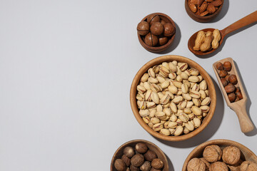 Various nuts in wooden bowls on a gray background
