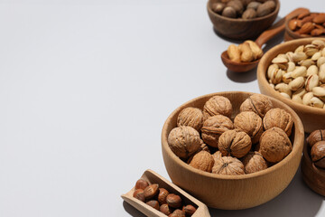 Various nuts in wooden bowls on a gray background