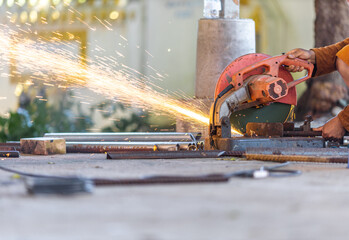 Blurred background of a craftsman using a machine, a saw blade cutting metal and sparks of scrap metal coming out. Use of tools and technology in construction.