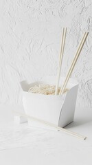 A chic noodle box with chopsticks stands out against a clean white backdrop
