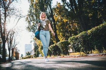 Full size photo of positive young blonde girl walking wear khaki outfit tied shoulders sweater park...