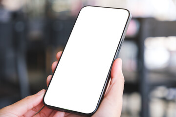Mockup image of a woman holding and using mobile phone with blank desktop in cafe
