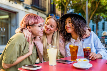 Cute friends embracing while drinking sodas and eat snacks outdoors