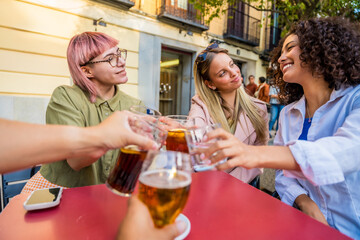 Friends toasting with beer in an outdoor terrace at bar