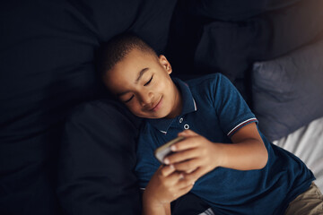 Boy, bed and positive with smartphone for video games, entertainment and subscription at home. African person, kid and happiness in bedroom on internet or online with streaming for child development