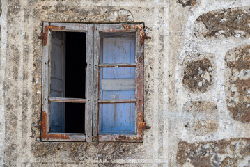 Picturesque rustic old window with wooden frames and blue shutters in a stone house