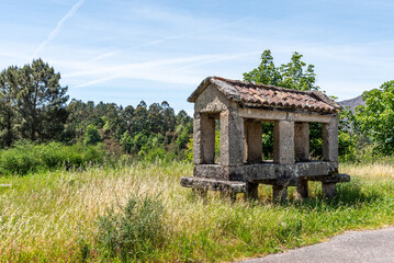 Historic stone granary stands amid lush greenery under a clear blue sky, embodying rural...