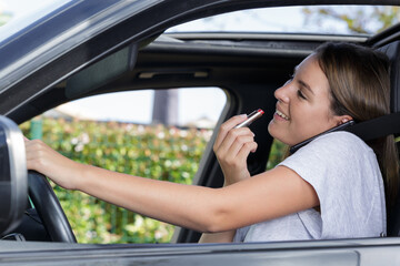 woman putting on lipstick in a car