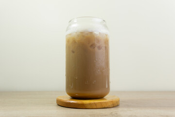 Ice cappucino on the wooden table with milk froth.