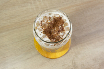 Ice cappucino on the wooden table with milk froth.