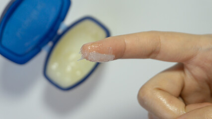 The index finger scoops up the petroleum jelly isolated on white background