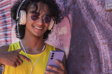 Young man with headphones listening to music and dancing urban dances on the street