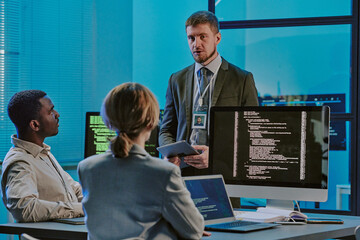Group of three diverse young people discussing issues during meeting in modern cybersecurity...