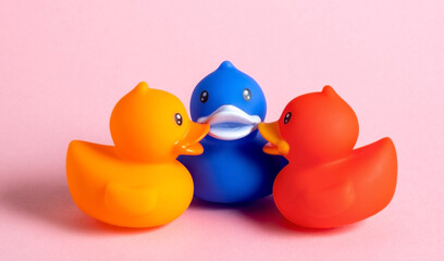 Three rubber ducks on a pink background.