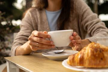 Woman drinking morning coffee of tea at breakfast table. Cup with copy space