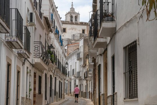Young person in sportswear walking through the narrow medieval stone streets of alburquerque.