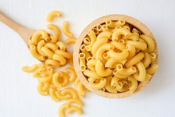 Raw uncooked macaroni in a wooden bowl on a white background	