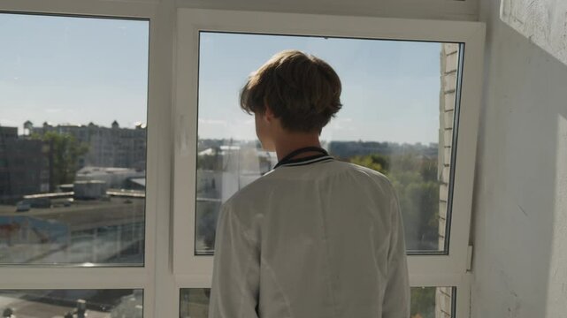 Future doctor. little boy kid child wearing doctor's white robe and stethoscope, dreaming about working at hospital clinic, looking at window. Children and medical occupation. 