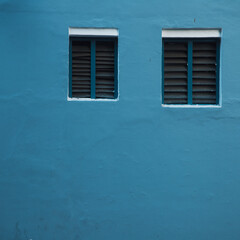 blue wall with two windows and horizontal lines of windows in a blue wall, blue concrete background
