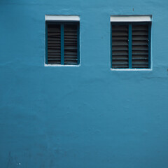 blue wall with two windows and horizontal lines of windows in a blue wall, blue concrete background