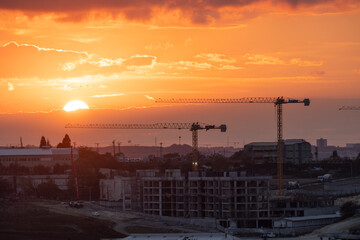 Fototapeta premium Sunset over a construction site with multiple cranes