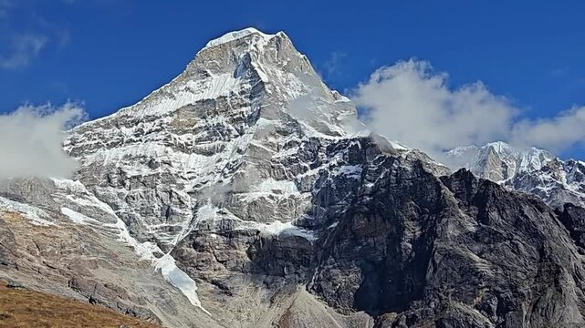 A breathtaking view of a towering snow-capped mountain peak against a clear blue sky, showcasing the rugged texture of the rocky terrain and the pristine beauty of nature