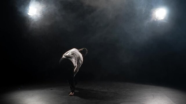 Solo dance of professional female dancer, young adult woman jumping in darkness. Slow motion shot with whirling dance performer on stage or in rehearsal room, active pastime and hobby, be in motion