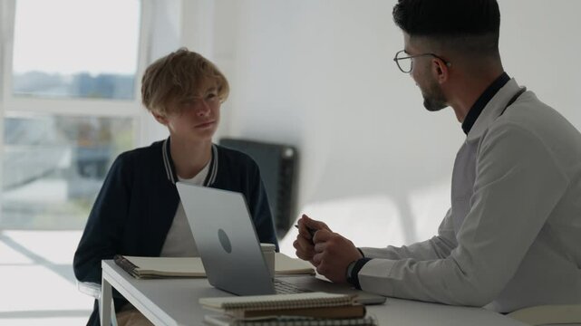 Caucasian child boy suffering from cold fever or allergy, sneezing, complaining to male man doctor at hospital clinic. Kid teenager school guy having flu in autumn, cold symptoms 