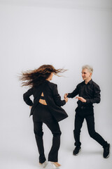 Fototapeta premium Passionate performance. Stylish couple, man and woman dancing bachata against dark green background. Concept of dance, performance, art, emotions, entertainment