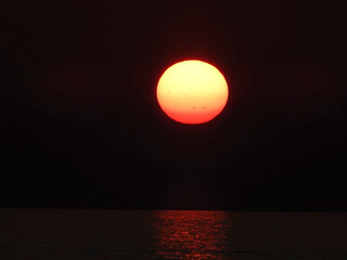 extremely zoomed sun at the sunset by the sea